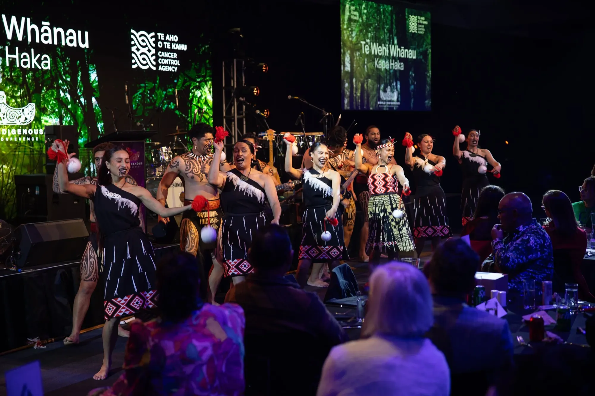 Te Wehi Whānau kapa haka rōpū performing to the room at the World Indigenous Cancer Conference gala dinner, Tāmaki Makaurau, April 2026